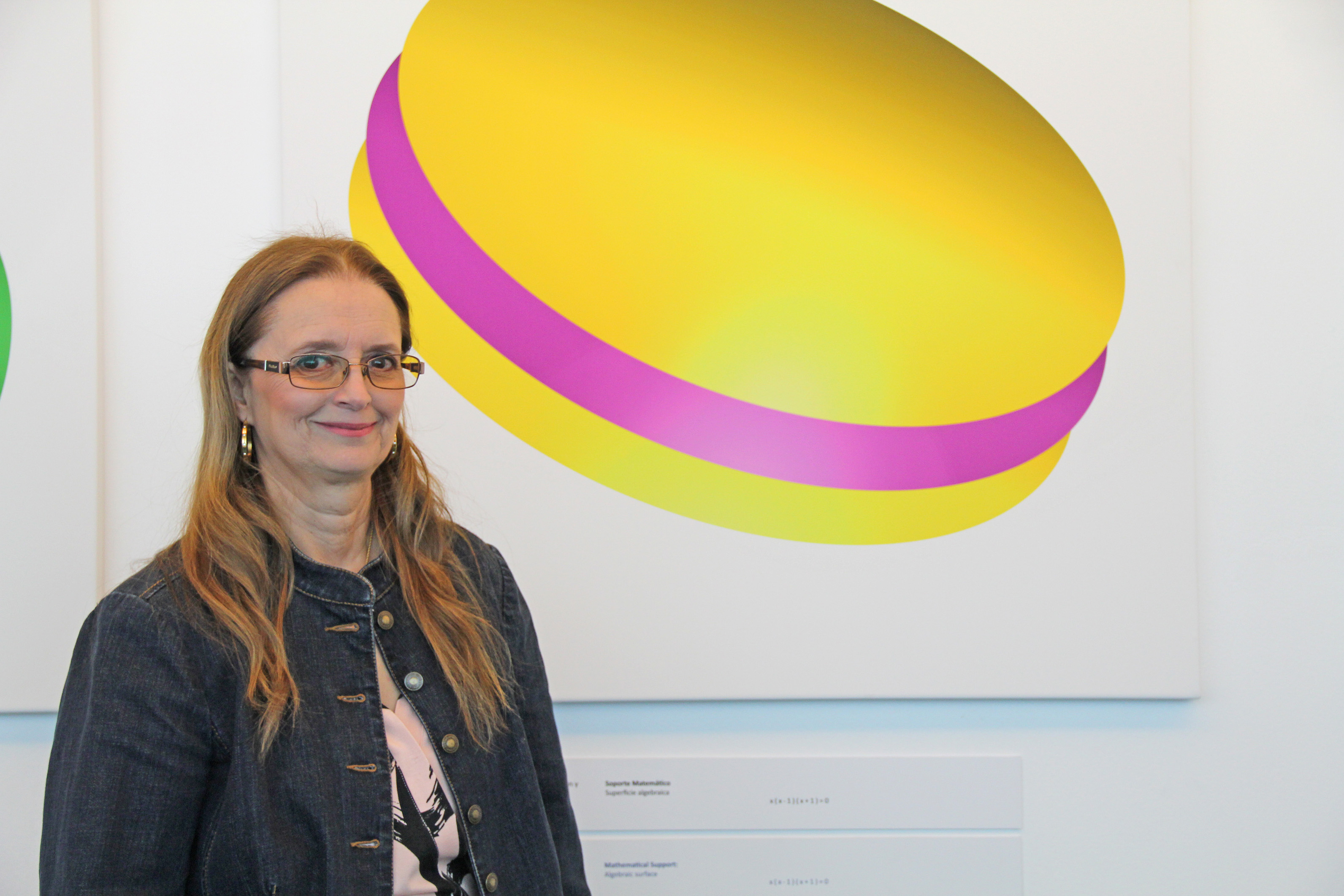 Regina Bittencourt standing with her mathematical art paintings Cala Lily and Le Macarron